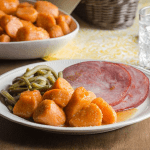 Candied Sweet Potatoes with Ham and Green Beans on a White Plate
