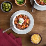 Turkey and Sweet Potato Chili in a White Bowl with a Dollop of Sour Cream topped with Scallions