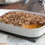 A Sweet Potato Casserole topped with Pecans in a White Baking Dish